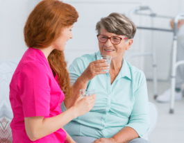 Young nurse drinking water and chatting with friendly senior woman