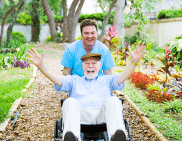 Caring nursing home orderly pops a wheelie with an elderly man's wheelchair