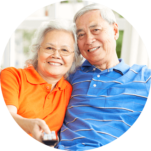 Senior chinese couple watching tv on sofa at home