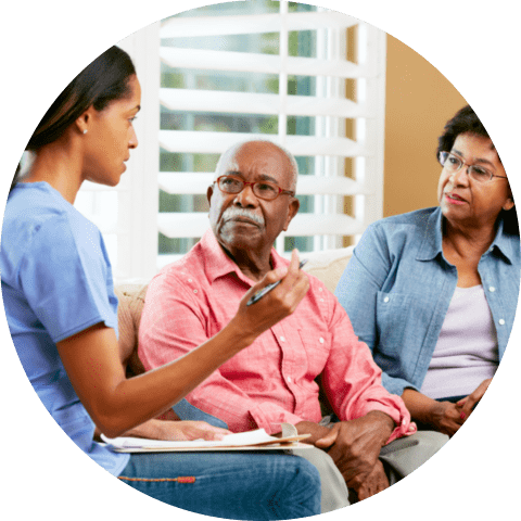 Nurse making notes during home visit with senior couple talking