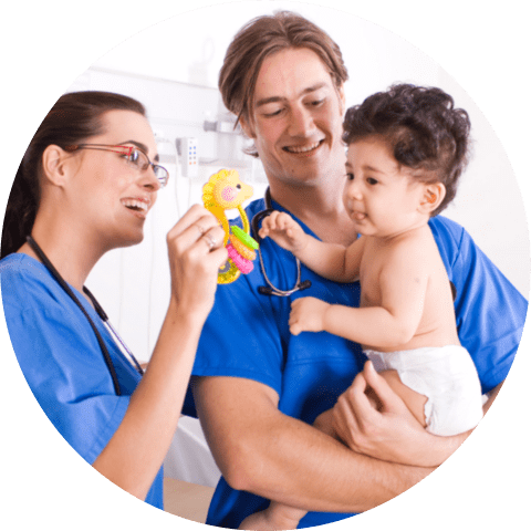 Two pediatricians playing with crying baby boy patient