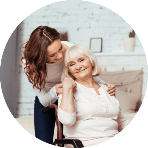 Pleasant elderly women smiling and sitting in the wheelchair with her caregiver