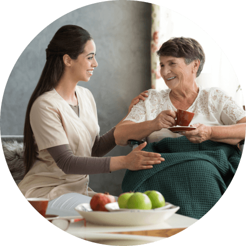 Young nurse serving coffee to senior lady