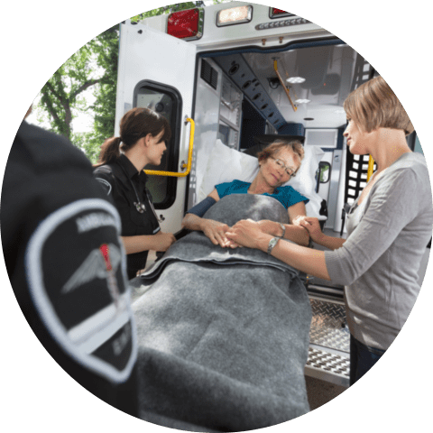 Senior women being loaded onto ambulance with caregiver at side
