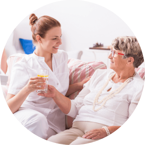 Senior women taking a glass of water from her young nurse